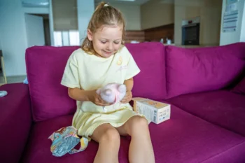 Holčička sedí na gauči a má na klíně Labubu.