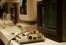 Před starou televizí leží retro herní konzole.