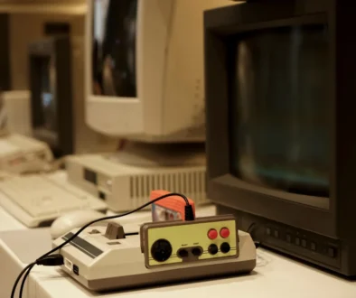 Před starou televizí leží retro herní konzole.