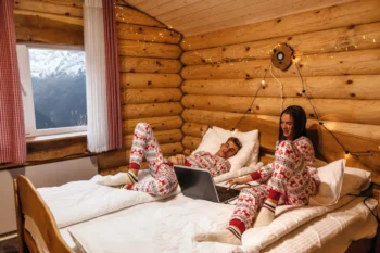 Lidé jsou oblečení do vánočních pyžam a v posteli se dívají na film.