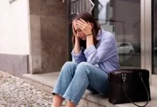 Mladá žena sedí před domem.