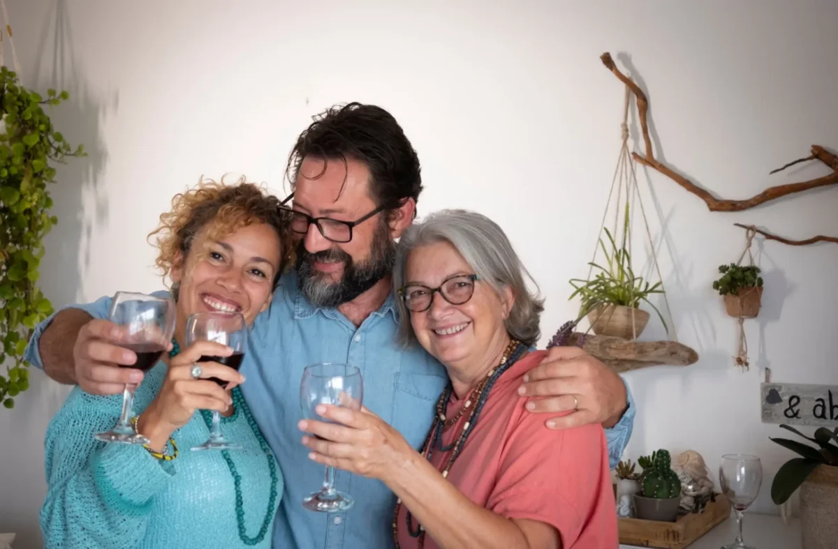 Muž kolem ramen drží dvě ženy.