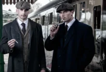 Dva muži stojí na vlakovém nástupišti.