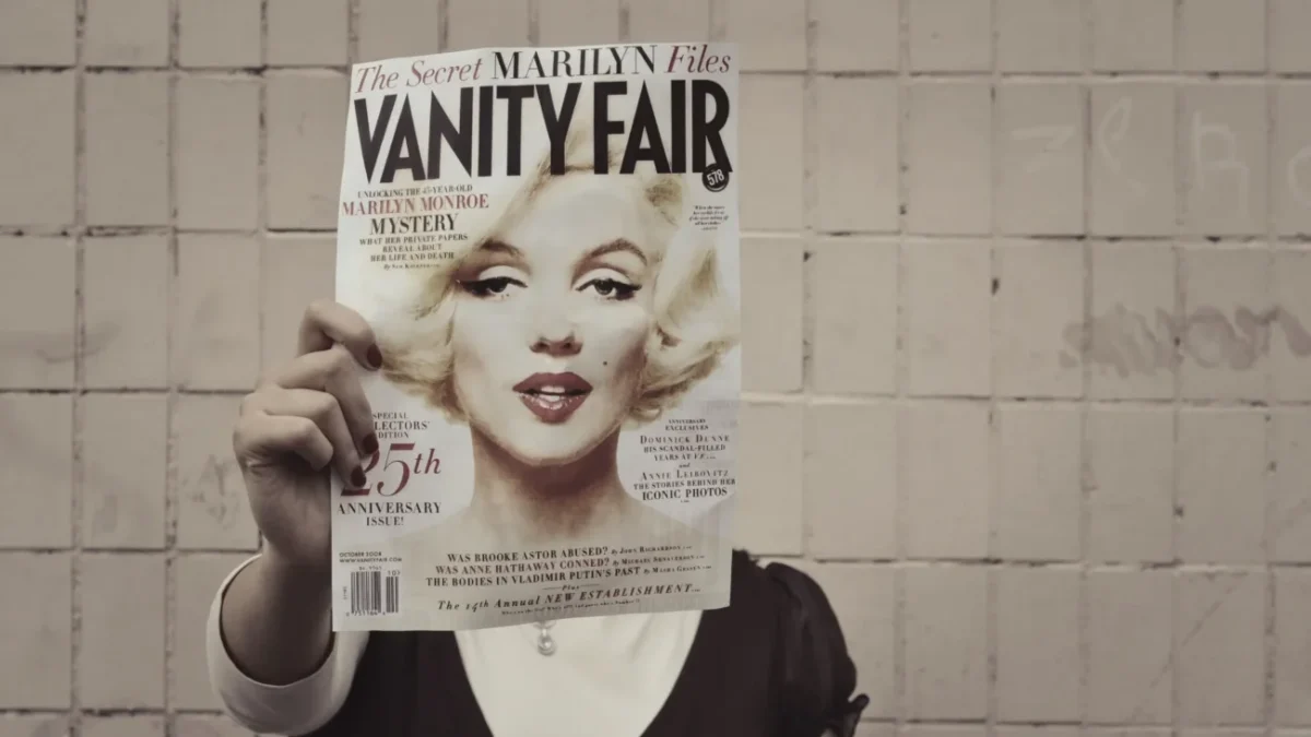 Člověk si před hlavou drží časopis s Marilyn Monroe.