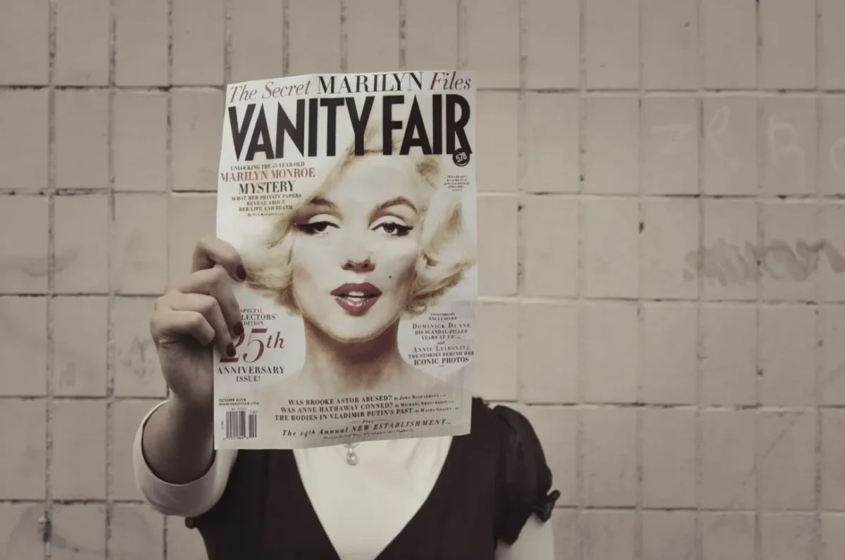 Člověk si před hlavou drží časopis s Marilyn Monroe.
