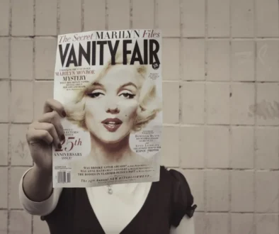 Člověk si před hlavou drží časopis s Marilyn Monroe.