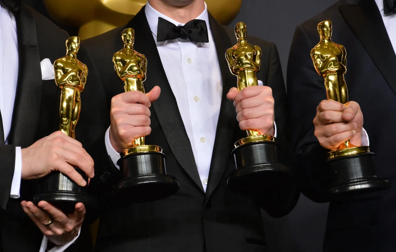 Tři muži drží ocenění Oscar. 