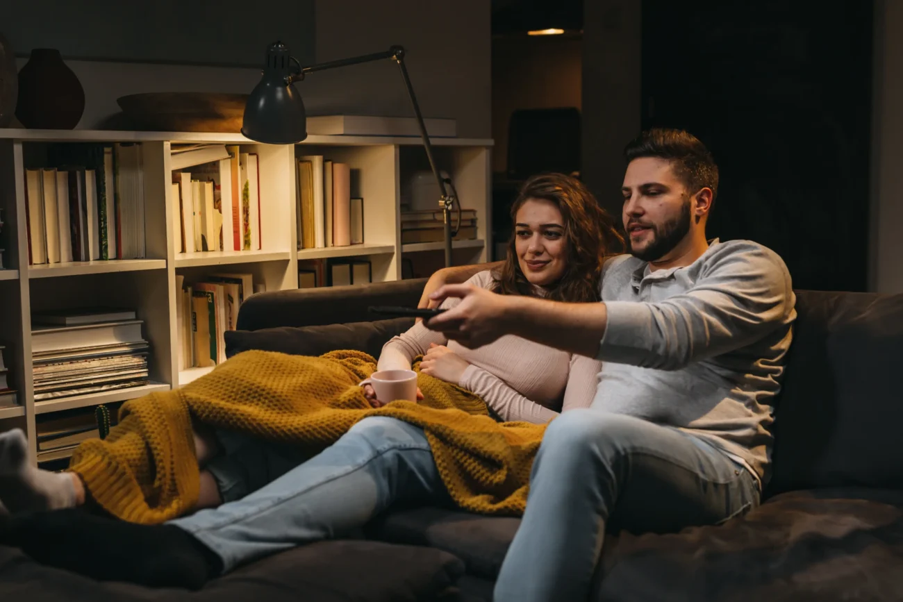 shutterstock_2052095588-2 | TVGURU.cz Muž se ženou sedí na gauči a dívají se na TV.