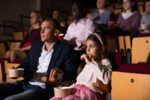 Tatínek s dcerou sedí v kině.