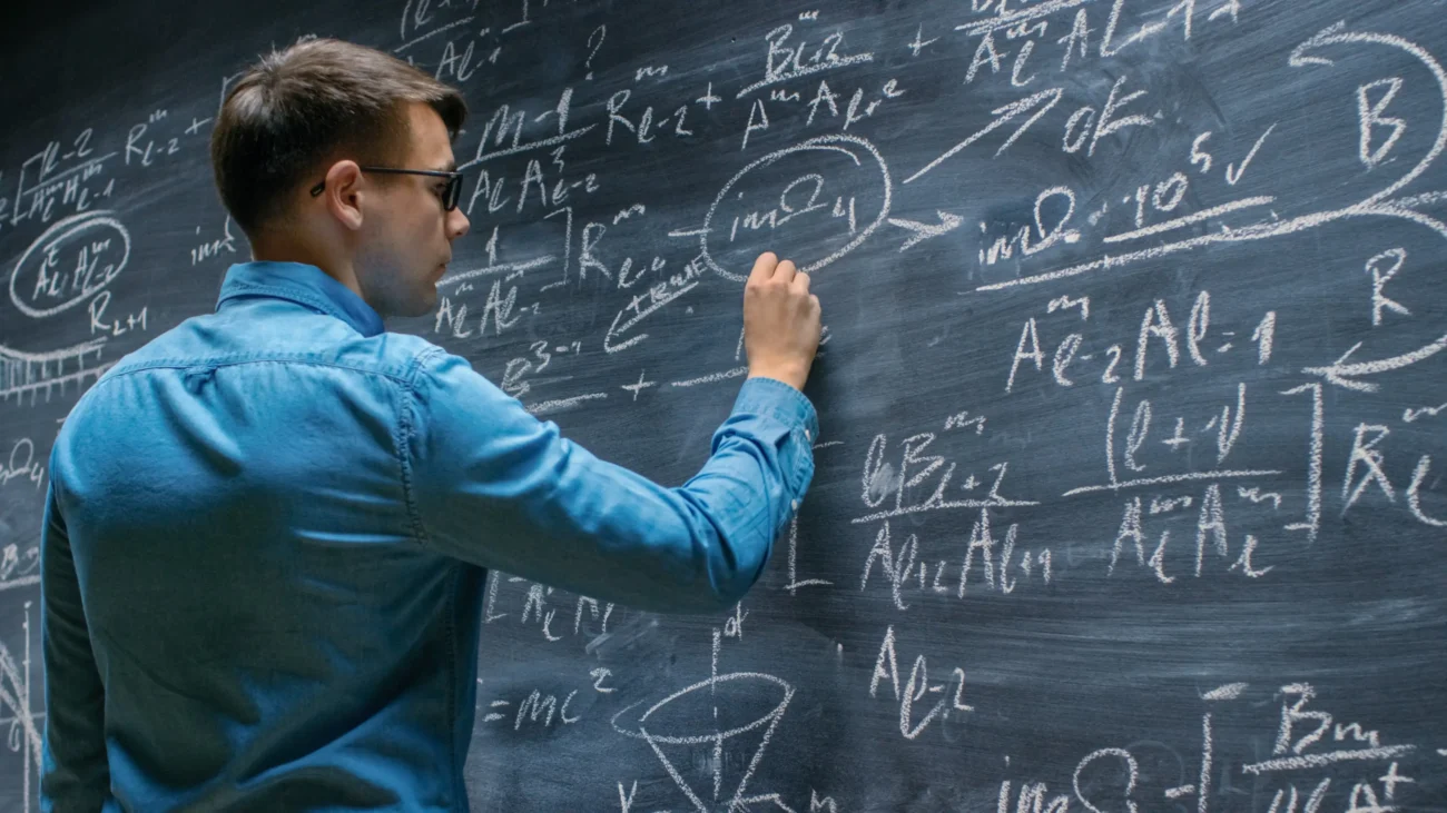 shutterstock_1101286898 1 | TVGURU.cz Muž píše matematické příklady na tabuli.