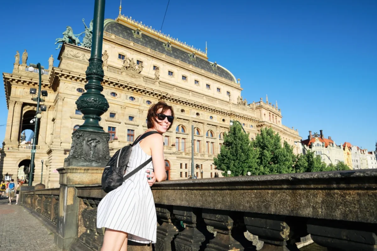 Žena se fotí v Praze před divadlem.