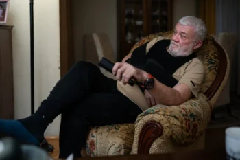 Starý muž sedí v křesle a dívá se na TV.