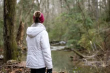 Žena stojí v přírodě.