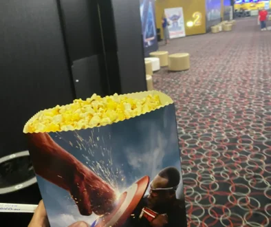 fotografie popcornu v ruce a v pozadí sál kina