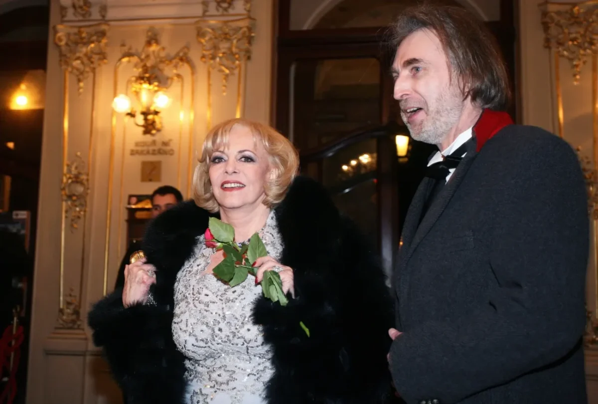 Michele Mercier stojí vedle muže a s úsměvem drží v ruce růži