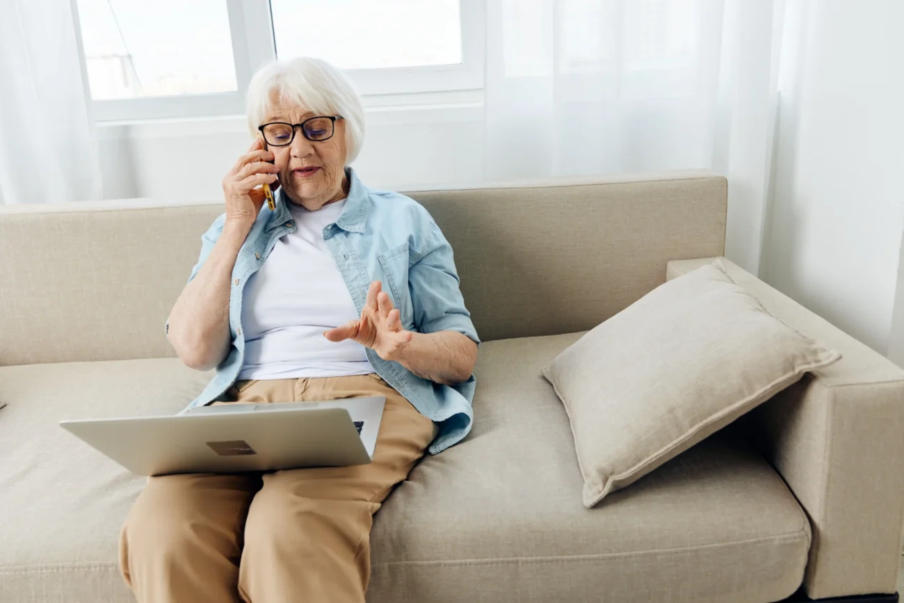 shutterstock_2190344485-2 | TVGURU.cz Babička sedí na gauči s notebookem.