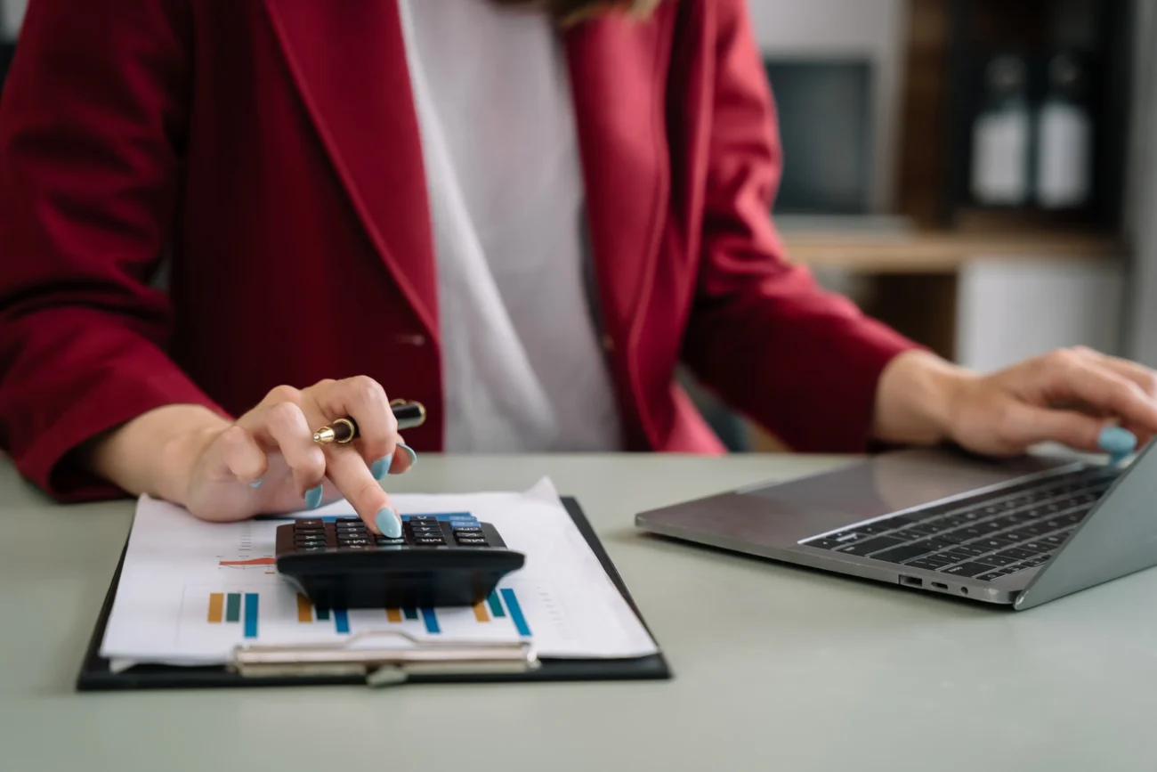 Žena ťuká do kalkulačky do notebooku. 
