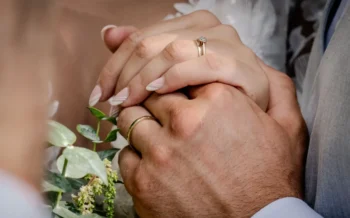 dva lidé se láskyplně drží za ruce na svatbě