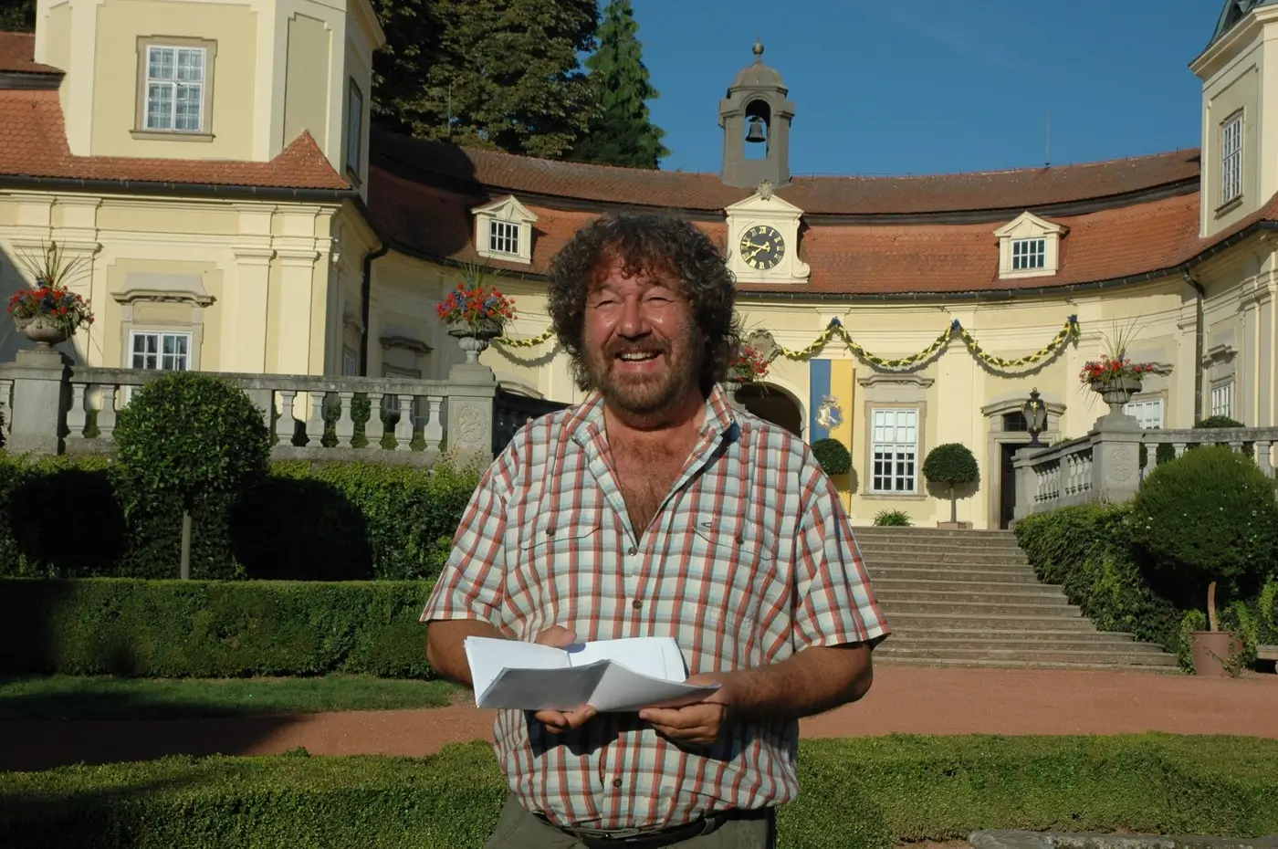profimedia-0156253920 | TVGURU.cz Zdeněk Troška v košili stojí před zámkem a usmívá se