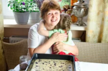 Žena společně s holčičkou sedí u upečené buchty.