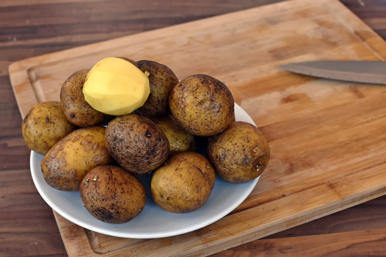 shutterstock_1708863595-2 | TVGURU.cz Na talíři na stole leží brambory.