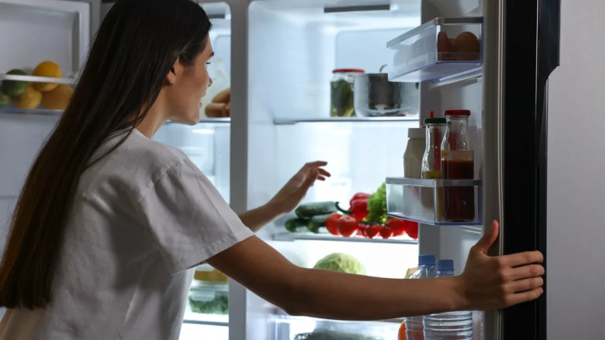 Žena kouká do otevřené lednice.