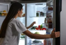 Žena kouká do otevřené lednice.