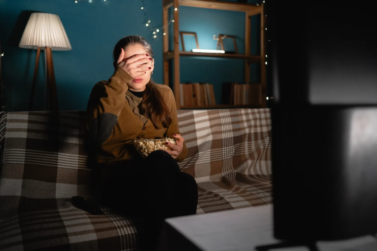 Vyděšená žena před televizí.