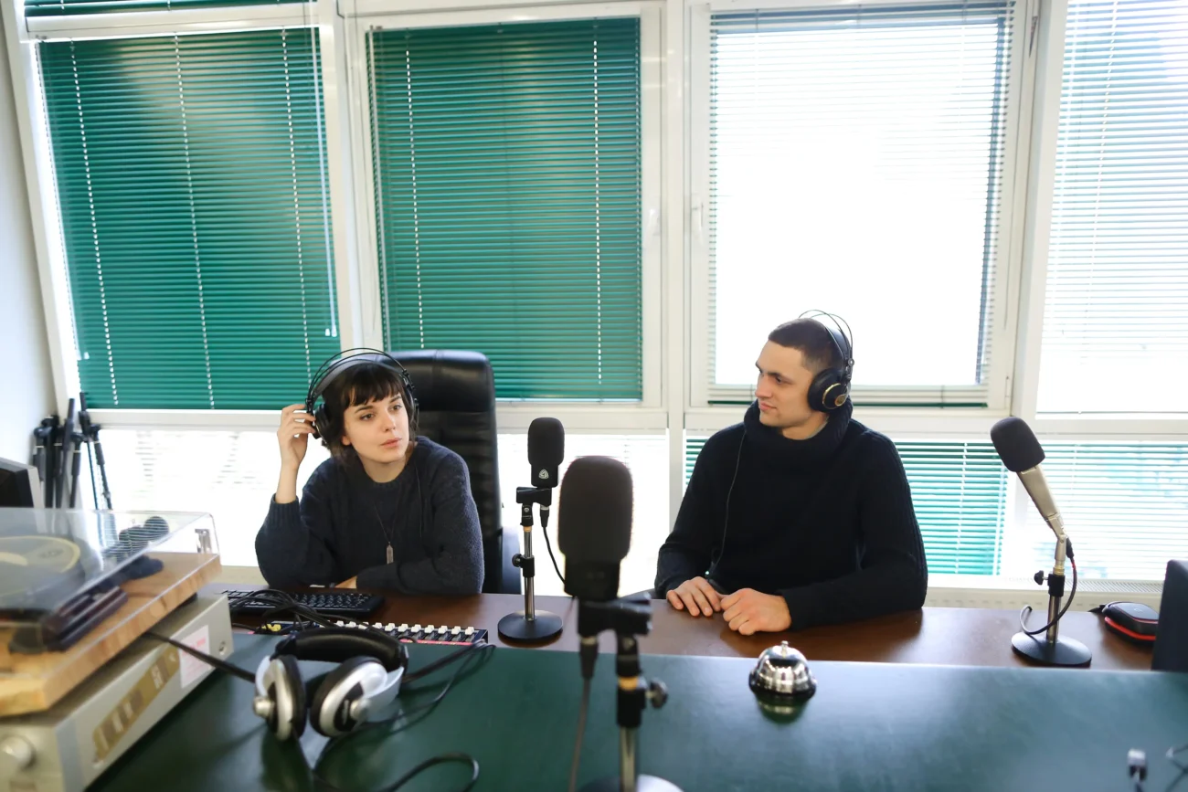 shutterstock_706788301-2 | TVGURU.cz Dva mladí lidé sedí u mikrofonů.