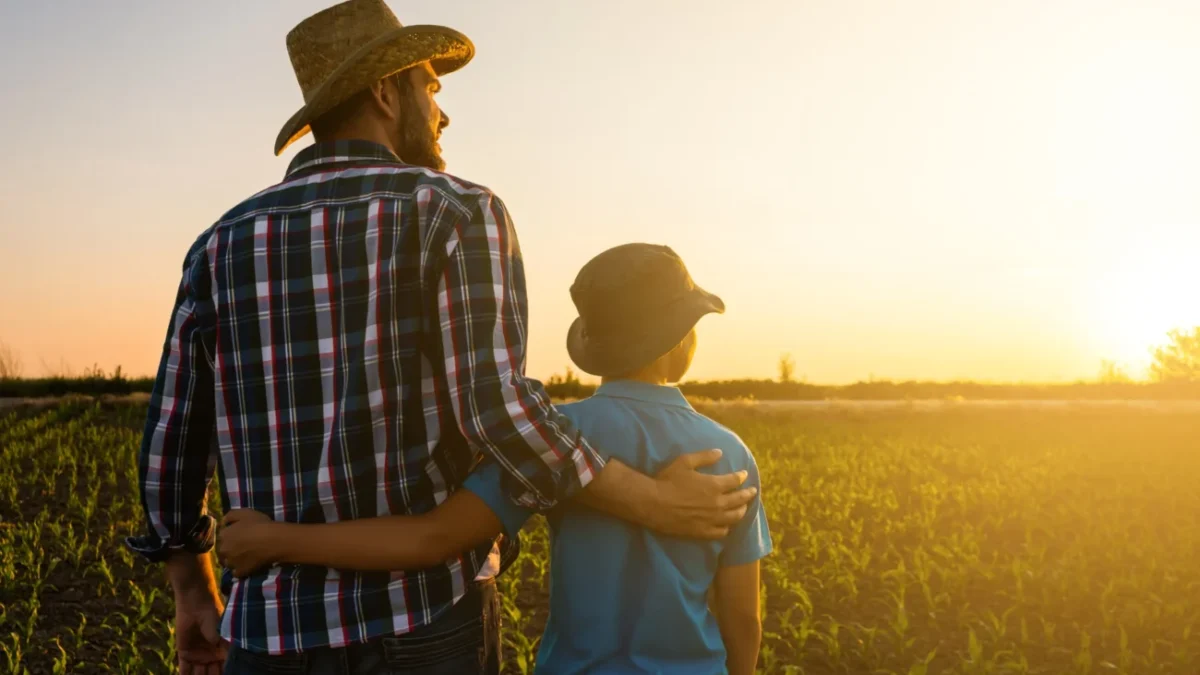 shutterstock_1986750245 1 Otec a syn stojí na poli při západu Slunce.