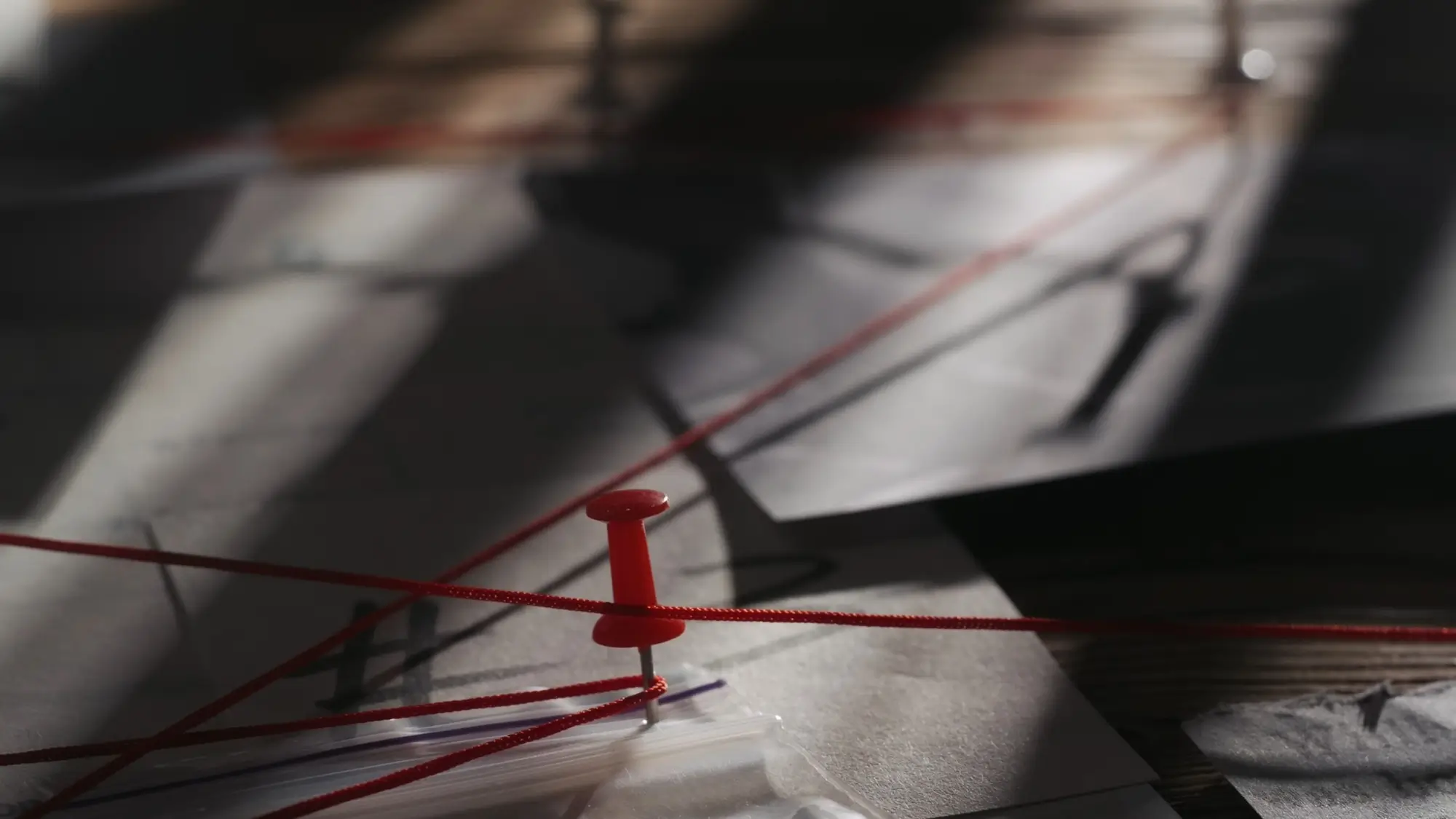 dokumenty vyšetřovaného případu s červenými nitkami sbíhajícími se u špendlíku