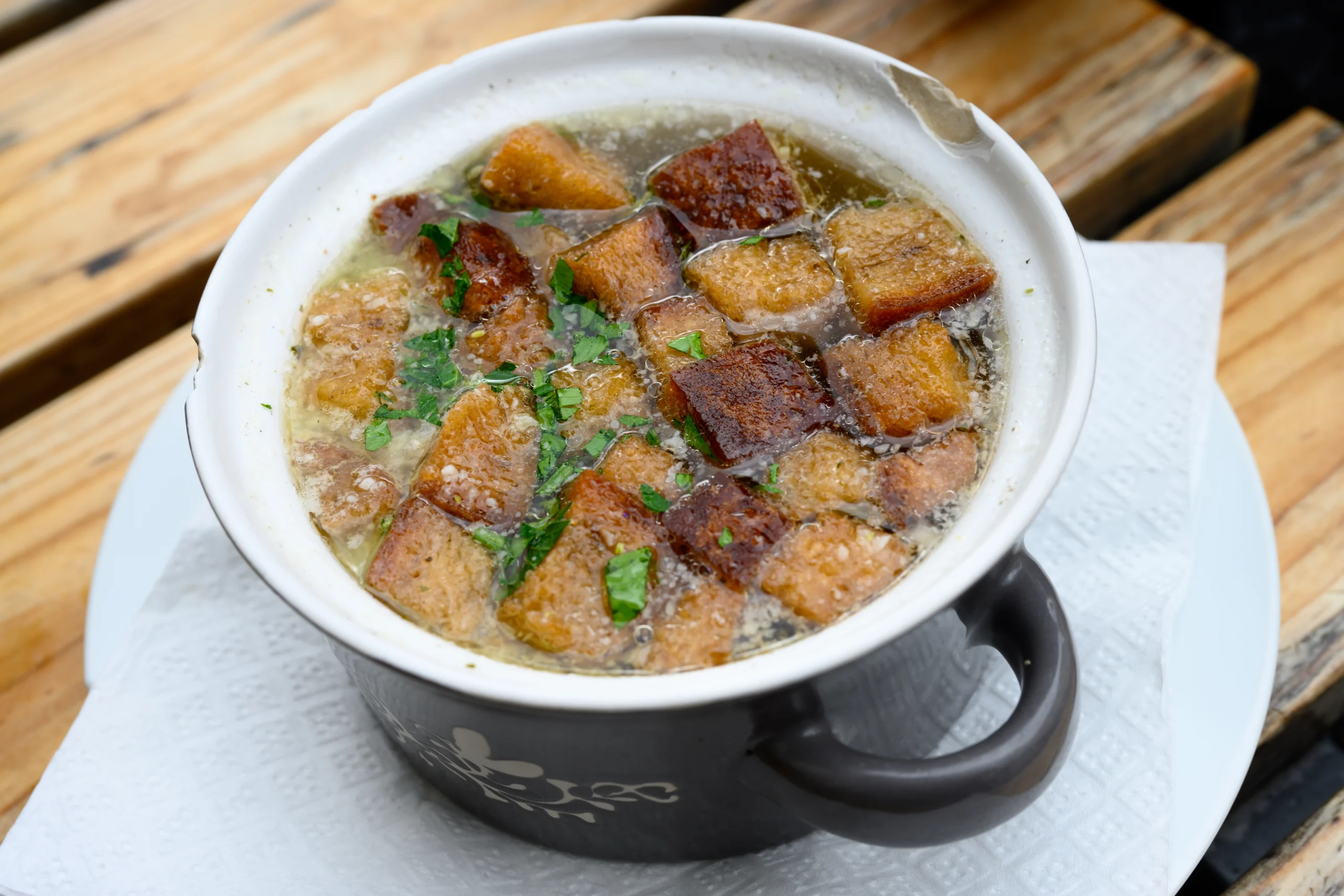 Miska česnekové polévky s kostky chleba na povrchu 