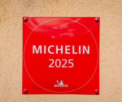 Klasické červené označení "michelinské restaurace" (2025) na zdi budovy
