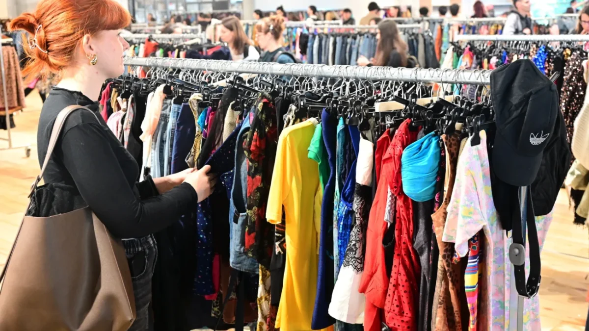 Žena si projíždí stojan s oblečením.