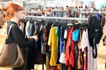 Žena si projíždí stojan s oblečením.