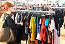 Žena si projíždí stojan s oblečením.