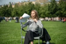 žena sedí venku, je jí horko, ovívá se