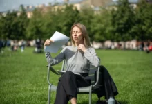 žena sedí venku, je jí horko, ovívá se