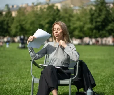 žena sedí venku, je jí horko, ovívá se