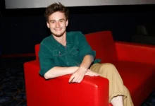 ondřej stupka sedí v červeném křesle a usmívá se