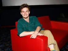 ondřej stupka sedí v červeném křesle a usmívá se