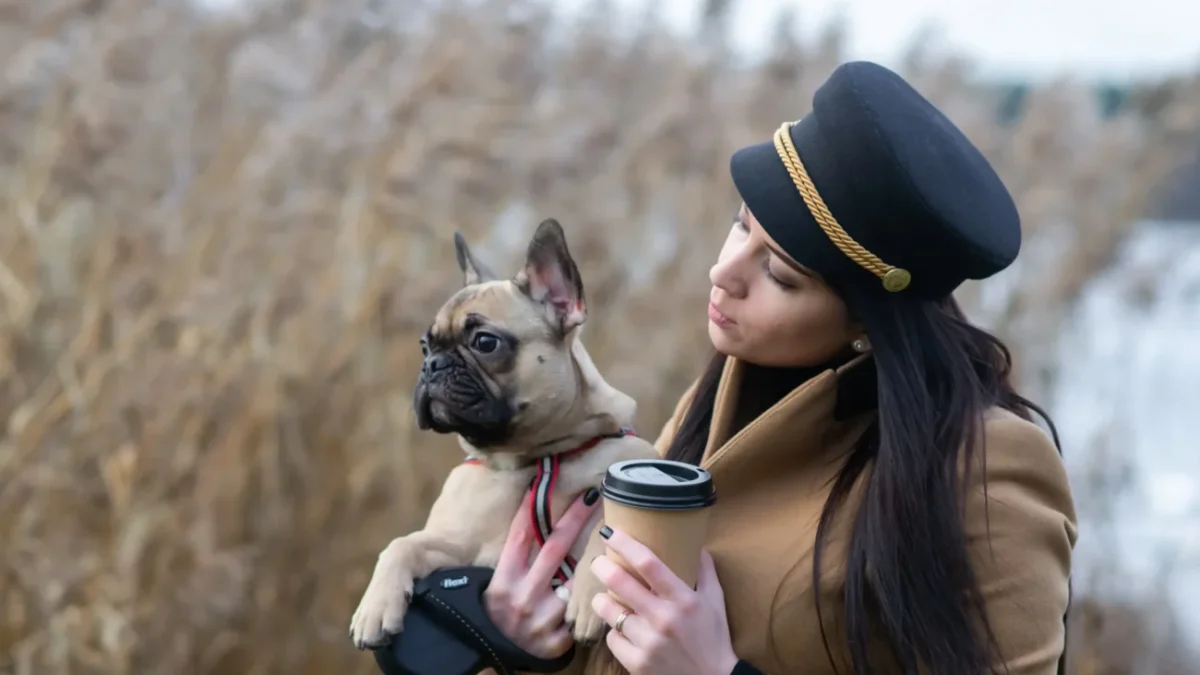 Žena v ruce drží kávu a pejska.