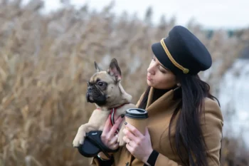 Žena v ruce drží kávu a pejska.