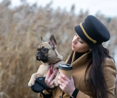 Žena v ruce drží kávu a pejska.