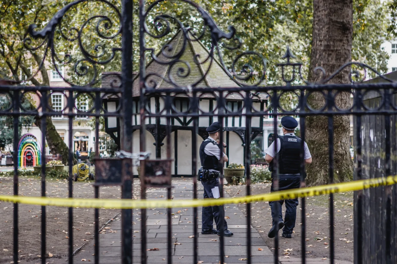 Za policejní páskou chodí policisté. 