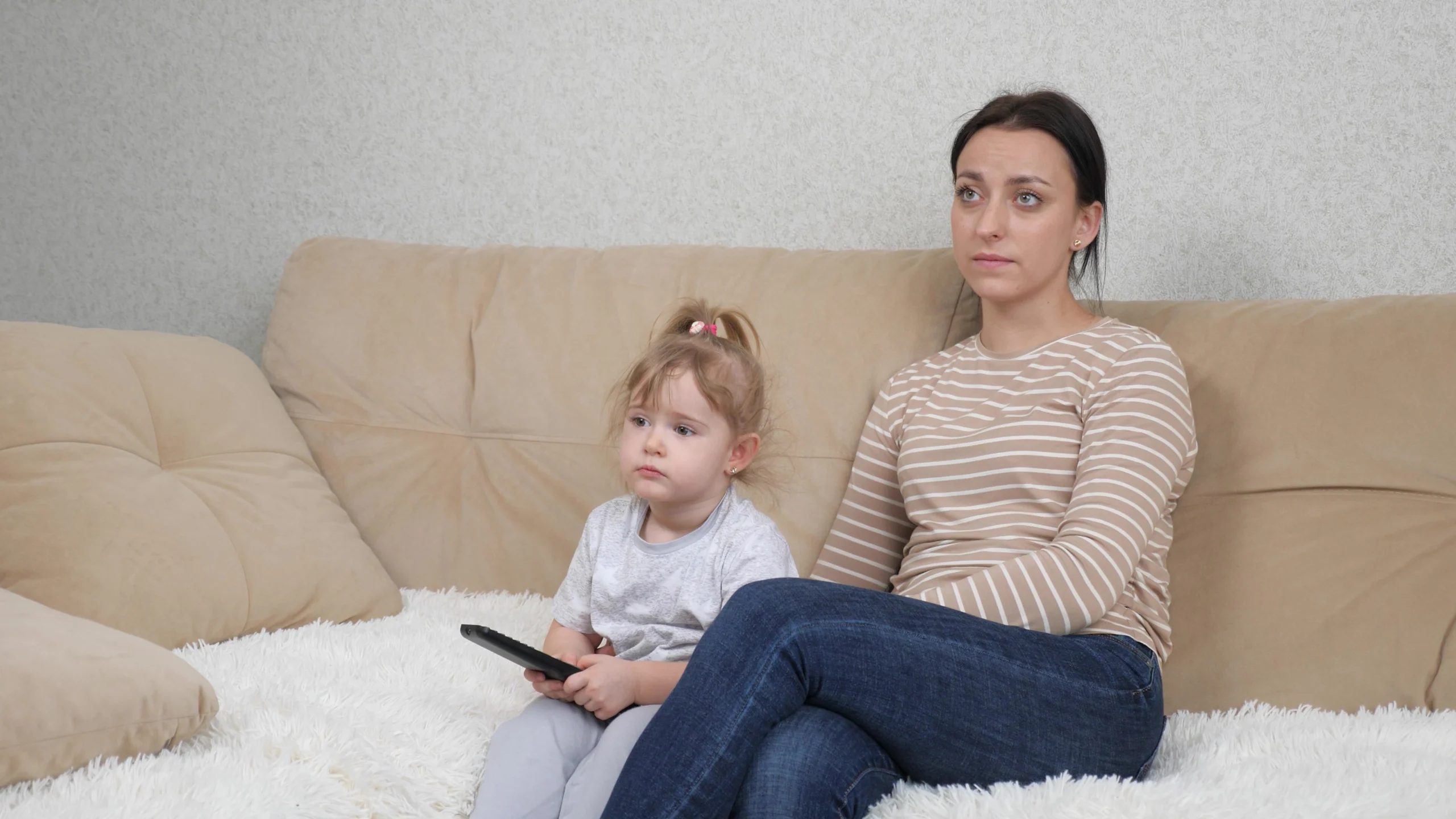 Smutná matka se znuděnou dcerkou doma na pohovce sledují film.