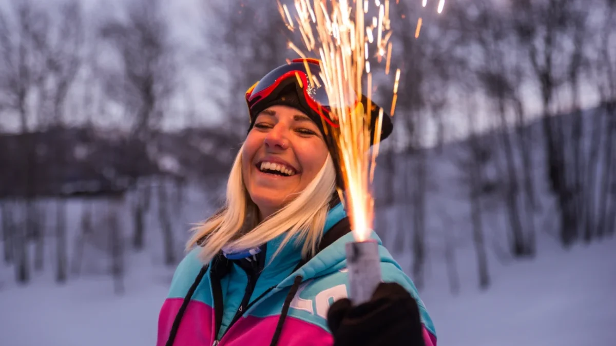 Žena se směje a v ruce drží pyrotechniku.