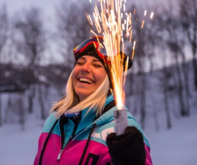 Žena se směje a v ruce drží pyrotechniku.