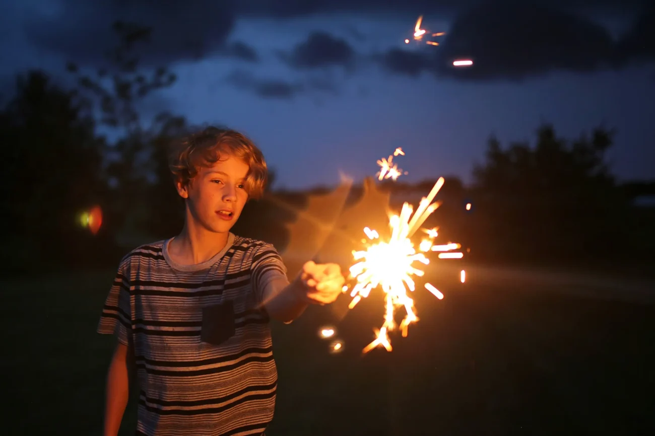 Chlapec v ruce drží prskavku. 