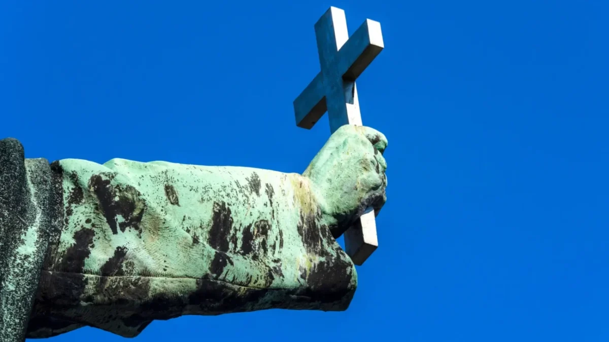 socha držící křesťanský kříž